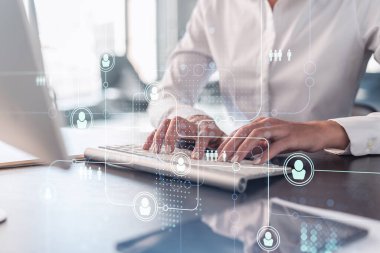 İK kadın uzmanı, işe alım sürecinde uluslararası ağ oluşturacak en iyi adayları bulmak için İnternet 'te klavyeyi yazıyor. Resmi kıyafet. Sosyal medya hologram simgeleri.