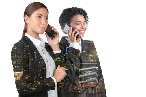 Two attractive businesswomen in suits talking phone. Asia corporate lifestyle, communication of diverse young professionals. Night Singapore city view. Double exposure — стоковое фото
