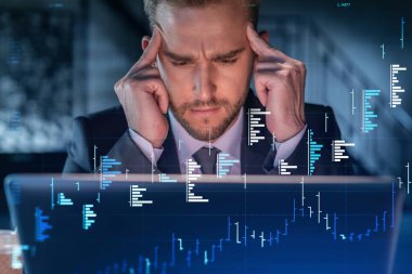 İş yerindeki takım elbiseli yakışıklı işadamı şirket finans fonundaki ticaret stratejisini optimize etmek için dizüstü bilgisayarla çalışıyor. Ofis arkaplanı üzerinde eski grafik hologramı