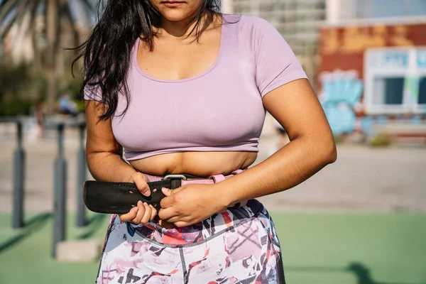 Crop etnische sportvrouw bevestiging gewichtheffen riem voor training op het strand — Stockfoto