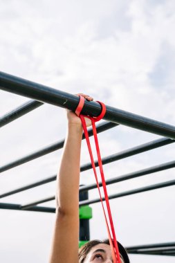 Azimli İspanyol sporcu kadın caddedeki yüksek barda egzersiz yapıyor.