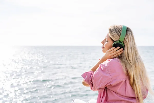 Woman listening to music in headphones on seashore — Stock Photo, Image