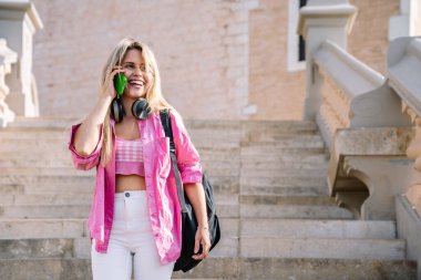 Şehirde akıllı telefondan konuşan mutlu, şık bir kadın.