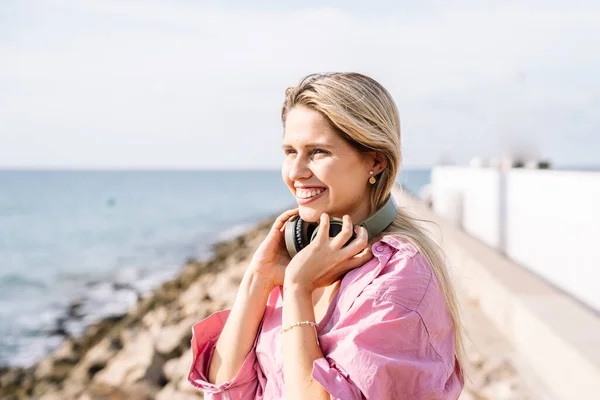 Femme écoutant de la musique dans les écouteurs sur le bord de la mer — Photo