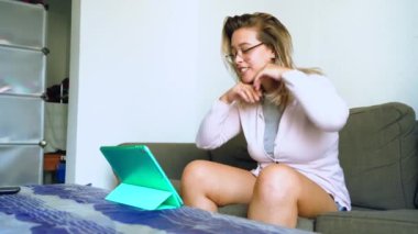 Tablette video konuşması yapan gülümseyen kadın.