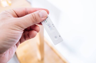 Adam evinde hızlı covid-19 testi yapıyor. 6 dalga covid 19 'dan dolayı pamuklu çubukla açılmamış test kaseti.
