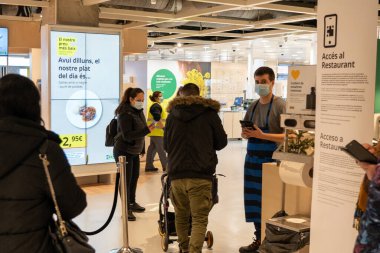 Barselona, İspanya, 21 Aralık 2021: Restoran müşterisi Ikea 'daki bir çalışana cep telefonundan Covid-19 sertifikası gösteriyor