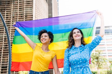 Gülümseyen lezbiyen çift LGBT bayrağı sallıyor