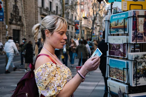 Femme qui choisit la carte postale dans la boutique de souvenirs de rue Photos De Stock Libres De Droits