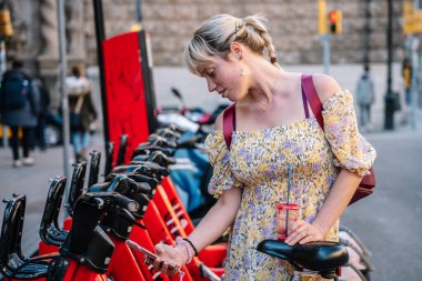 Bisiklet kiralamak için akıllı telefon kullanan kadın