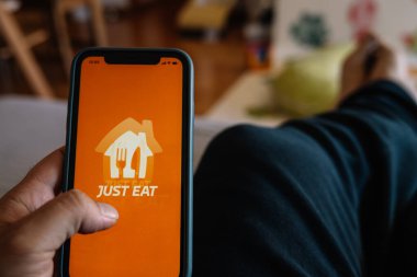 Barselona, İspanya, 15 Şubat 2022: Erkek eller akıllı telefonu tutuyor ve evde yemek yiyor.