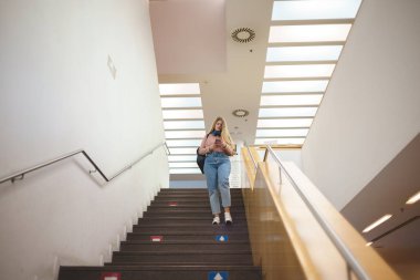 Üniversitede merdivenlerden inen bir kız öğrenci.