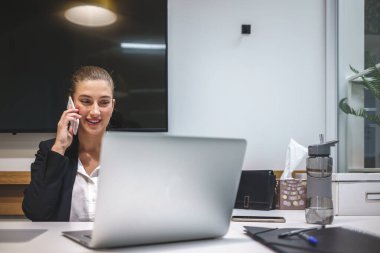 İş yerinde akıllı telefondan konuşan gülümseyen iş kadını