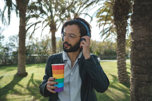 Man with LGBT cup listening to music