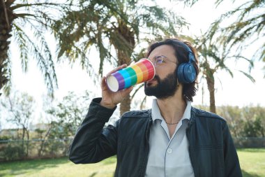 Kulaklıklı homoseksüel adam içki içiyor.