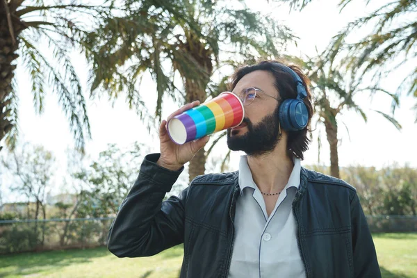 Kulaklıklı homoseksüel adam içki içiyor.