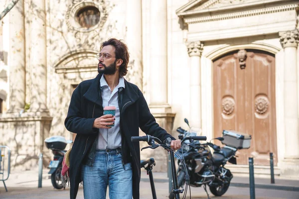  İş adamı bisikletini sürerken kahve içer. 