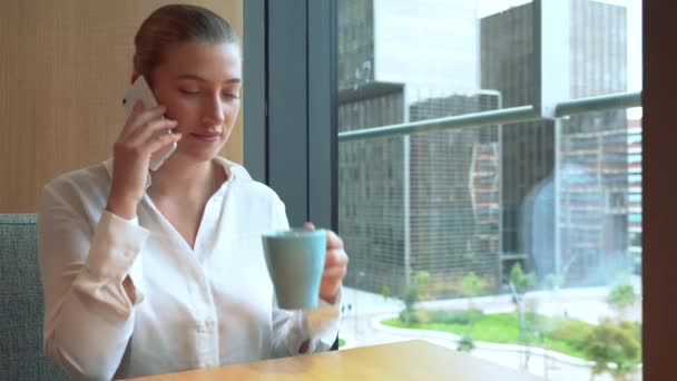 Female executive talking on mobile phone while having coffee at work. 4k — Vídeo de Stock