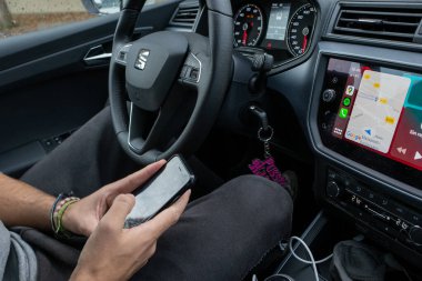 Barcelona, Spain, 19 July 2022: Man searching destination direction or address on gps or navigator application via mobile smartphone inside a car. High quality photo