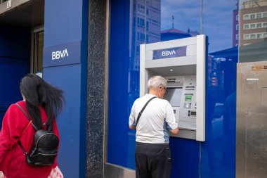 Gijon, Spain, 29 July 2022: elderly person withdrawing money from a bbva ATM. High quality photo