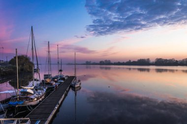 Gün batımında tekne dolu bir marina görüntüsü.