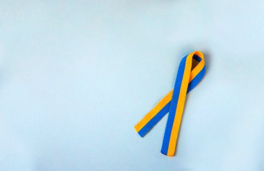Sarı-mavi (Ukrayna bayrağının renkleri) izole edilmiş dayanışma sembolik kurdelesi açık mavi arkaplanda yatar 