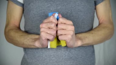 Erkeklerin elleri sarı-mavi Ukrayna bayrağını açıyor. Üzerinde 