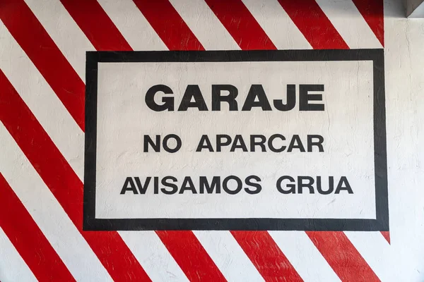 Garage warning sign, no parking, tow truck warning, painted on the wall at the entrance of a garage in Spanish.