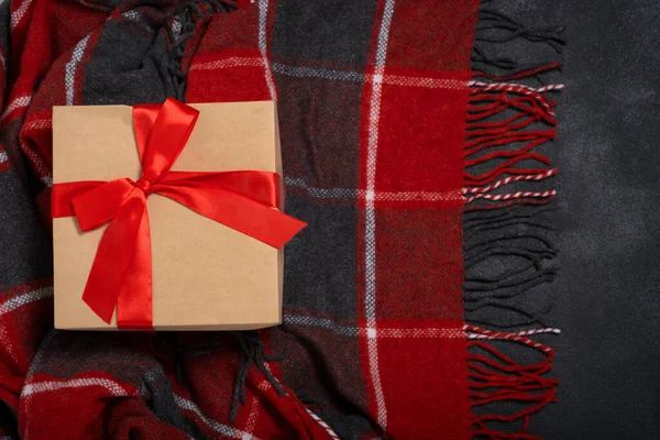 黒の背景に赤と黒のチェックが施された赤い弓を持つクリスマスギフトクラフトボックス — ストック写真