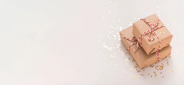 Beyaz-kırmızı yeni yıl kurdelesi ve bej arka plan fotokopi alanında altın konfeti yıldızlarıyla el işi kağıdında iki hediye kutusu. Noel, düğün