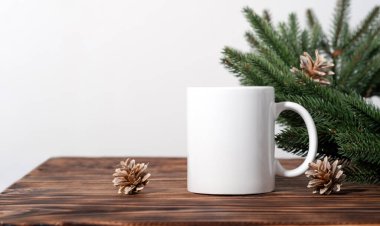 Kahverengi ahşap bir masada beyaz boş çay fincanları ve Noel ağacı çelengi dalları. Tasarımınız için kase şablonu, kopyalama alanı ile logo. Yeni Yıl