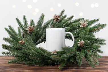Kahverengi ahşap bir masada beyaz boş çay fincanları ve Noel ağacı çelengi dalları. Tasarımınız için kase şablonu, kopyalama alanı ile logo. Yeni Yıl