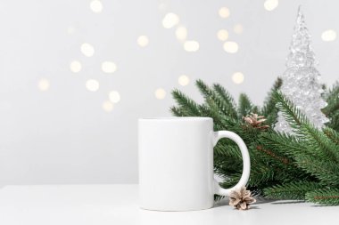 Noel 'de beyaz bir masaya beyaz çay fincanları ve Noel ağacı çelenklerinin dalları. Tasarımınız için kase şablonu, kopyalama alanı ile logo. Yeni Yıl