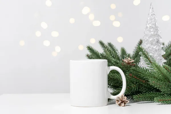 Noel 'de beyaz bir masaya beyaz çay fincanları ve Noel ağacı çelenklerinin dalları. Tasarımınız için kase şablonu, kopyalama alanı ile logo. Yeni Yıl