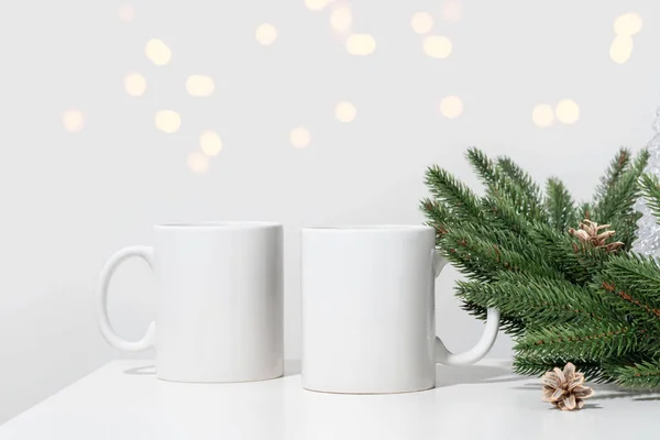 Noel 'de beyaz bir masada iki beyaz çay fincanı ve Noel ağacı çelengi dalları. Tasarımınız için kase şablonu, kopyalama alanı ile logo. Yeni Yıl