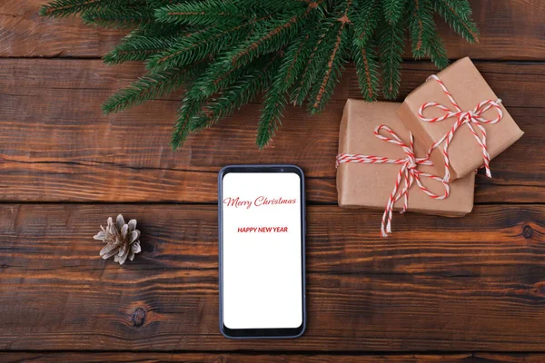Modern akıllı telefon ahşap vintage masa üzerinde, Noel süslemesi ve hediye kutusu ile birlikte. Düz şablon. Firavun çelengi