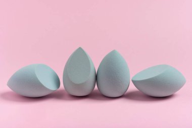Blue cosmetic makeup sponge on a minimal pink background. A set of sponges of different shapes. Tool for applying foundation cream. Nobody.