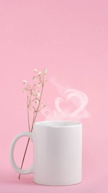 Beyaz kahve fincanı ya da pembe arka planda bir kupa. Kalp şeklinde sıcak içecek buharı.