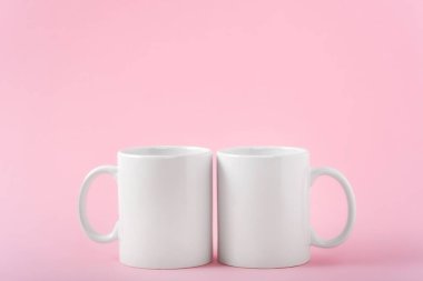 İki beyaz kahve fincanı ya da fincanı pembe arka planda fotokopi alanı olan bir kupa yap. Tasarım, marka ve iş için boş bir şablon. Gerçek fotoğraf.