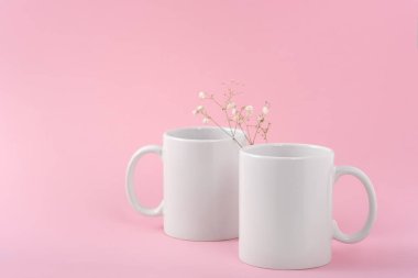 İki beyaz kahve fincanı ya da fincanı pembe arka planda fotokopi alanı olan bir kupa yap. Tasarım, marka ve iş için boş bir şablon. Gerçek fotoğraf.