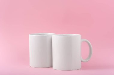 İki beyaz kahve fincanı ya da fincanı pembe arka planda fotokopi alanı olan bir kupa yap. Tasarım, marka ve iş için boş bir şablon. Gerçek fotoğraf.