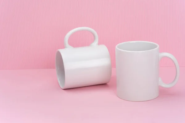 İki beyaz kahve fincanı ya da fincanı pembe arka planda fotokopi alanı olan bir kupa yap. Tasarım, marka ve iş için boş bir şablon. Gerçek fotoğraf.