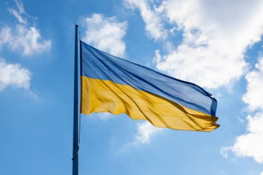 Mavi gökyüzü bulutlarında dalgalanan Ukrayna bayrağı. Büyük sarı Ukrayna ulusal bayrağı. Rusya Ukrayna 'ya saldırdı