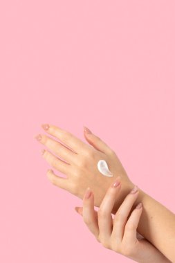 Pembe arka plan lekeli krem, uzun bej tırnaklar, manikür ve jöle cilası. Cildi ve vücuduyla ilgilenen bir kadın.