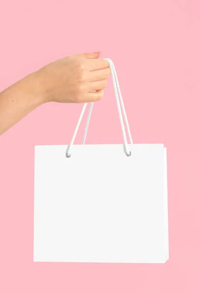 摩卡女手拿着一个白色的纸时尚包 包在粉红色孤立的背景上 设计和标识的空模板 — 图库照片
