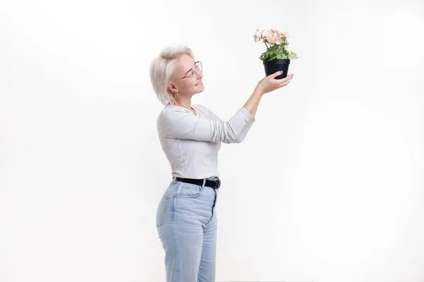 Blonde girl looks at flowers in a pot white background, banner — Stock Photo, Image