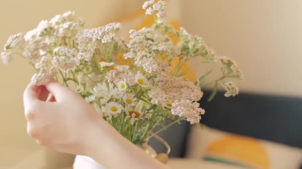 Menina endireita um buquê de flores silvestres em um vaso na mesa — Vídeo de Stock