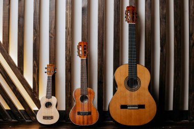 Müzik aletleri: ahşap bir arka planda üç farklı boyutta gitar