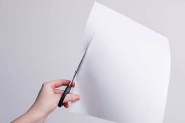 Bir kız beyaz kağıdı makasla keser. Yüksek kalite fotoğraf