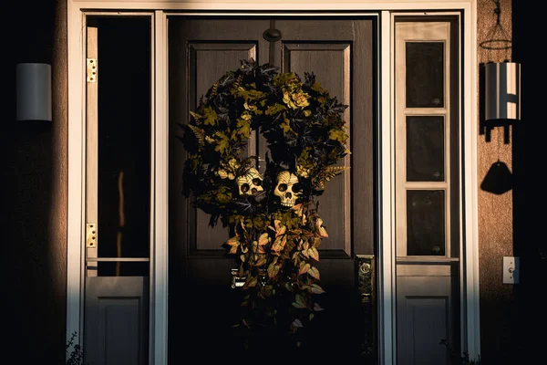 Herbstkranz mit menschlichem Schädelskelett an der Haustür. Szenerie für Halloween im Oktober. Dekoration im Hof. — Stockfoto